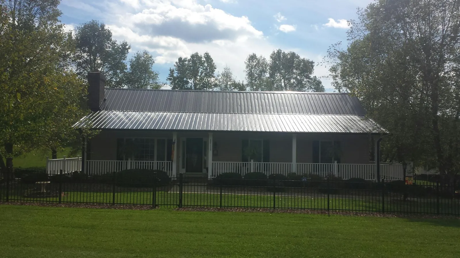 Gray metal roof on a brick ranch with a full width front porch — Gutter Guard Installation work by our crew in Meriden